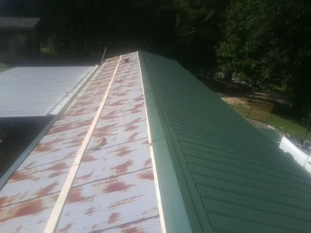 Old rusted panels beside newly installed green metal roofing — Wind Damage Roof Repair by Roofing Brothers in Calhoun Falls
