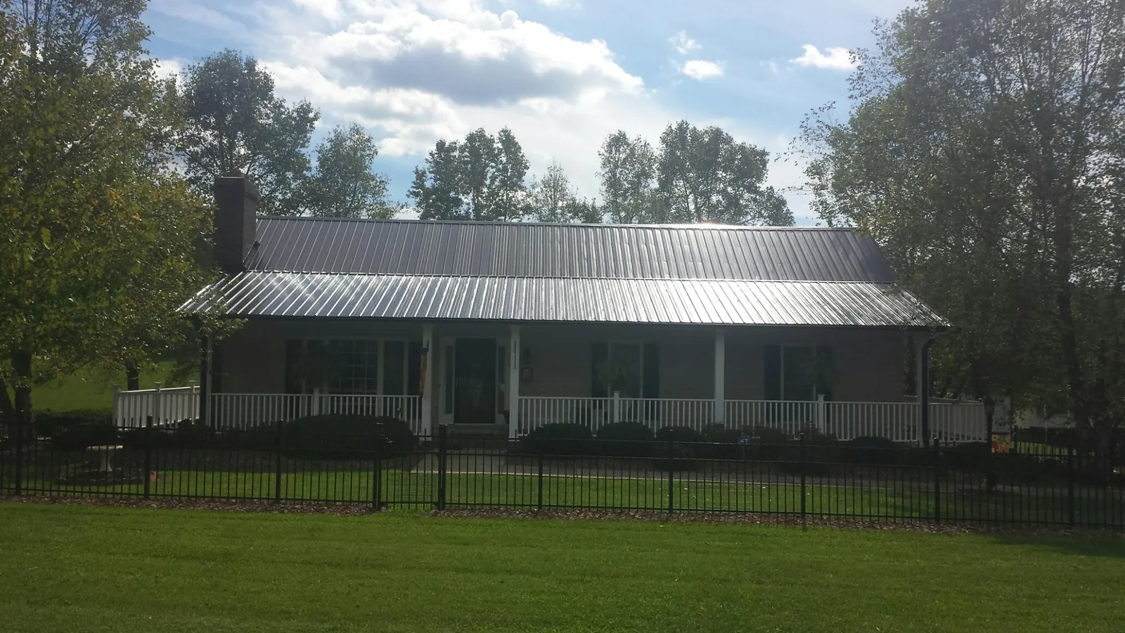 Gray metal roof on a brick ranch with a full width front porch — Gutter Guard Installation work by our crew in Calhoun Falls