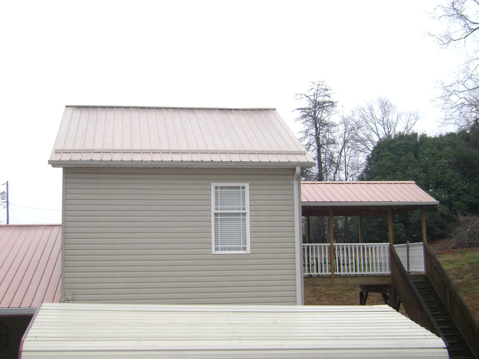 Tan metal roofs on a two story addition and attached porch, from a Roof Replacement job in Calhoun Falls