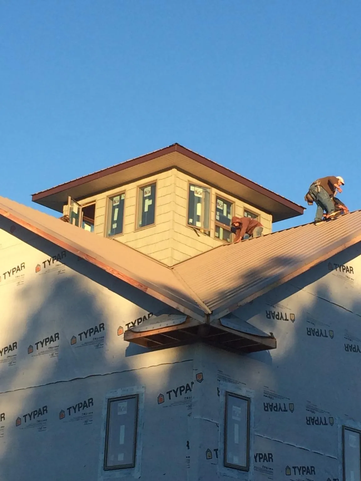 Roofers working around a rooftop cupola on a new metal roof at sunset — Roof Waterproofing in Calhoun Falls by Roofing Brothers